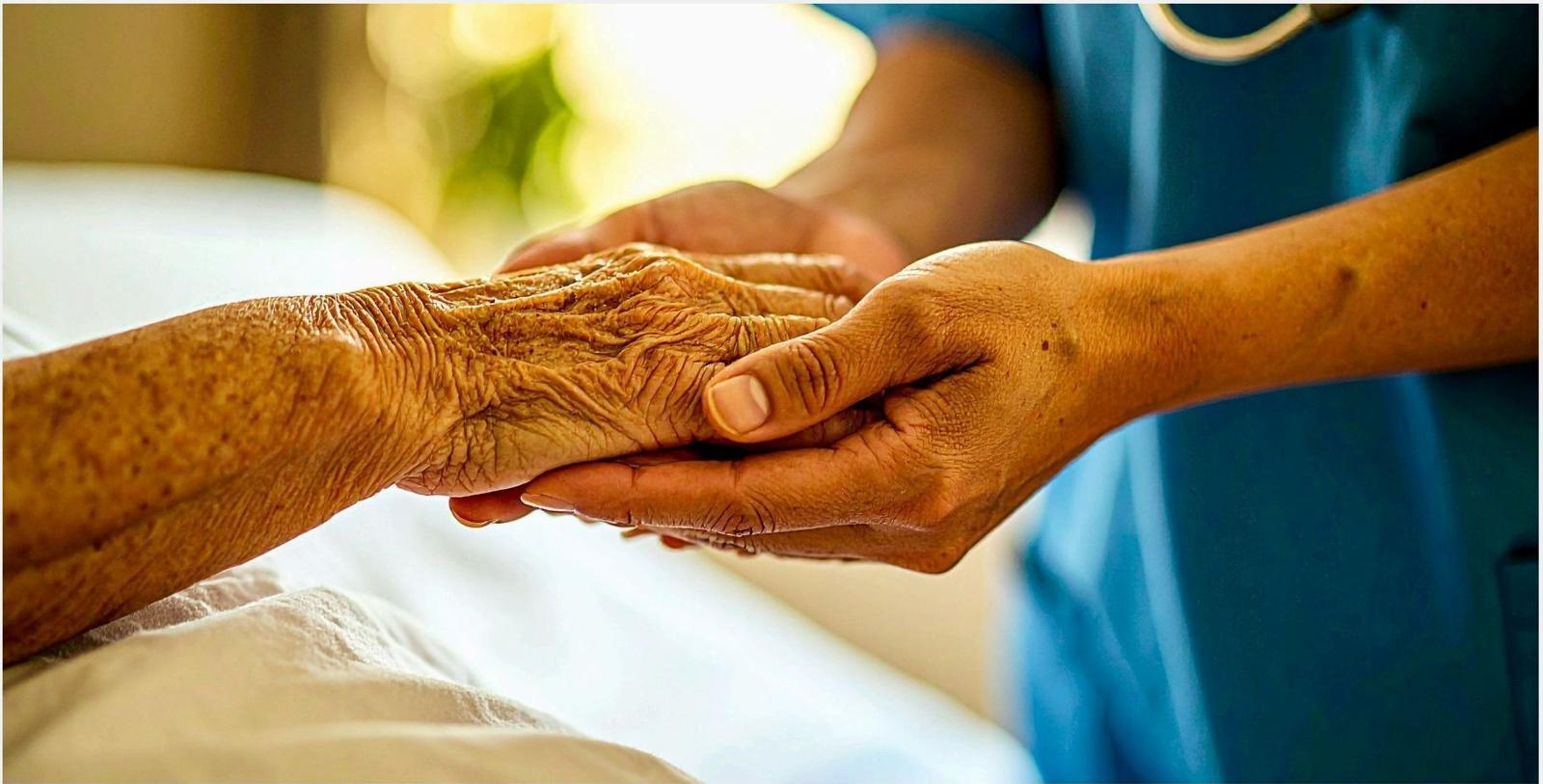 A caregiver gently holding the hand of an elderly person